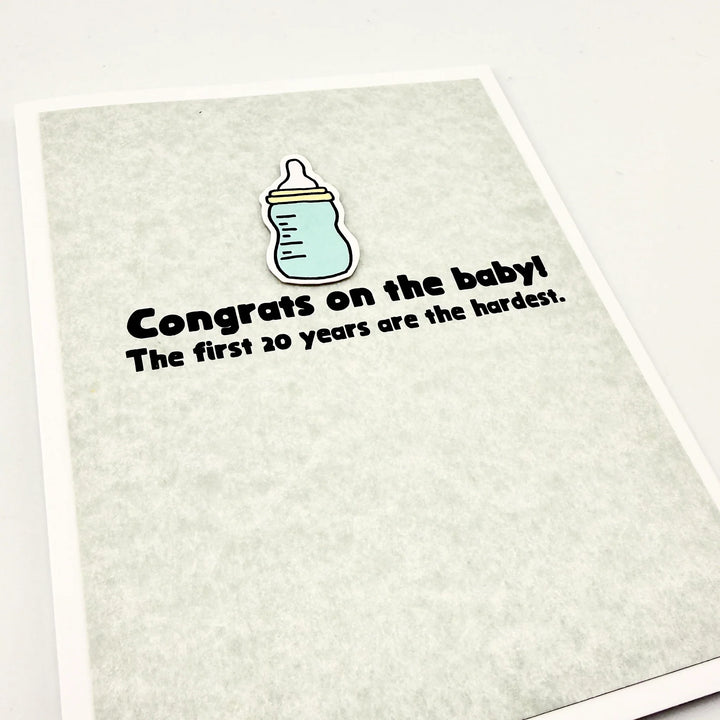 Baby Bottle cut out on card that says, "Congrats on the baby! The first 20 years are the hardest."