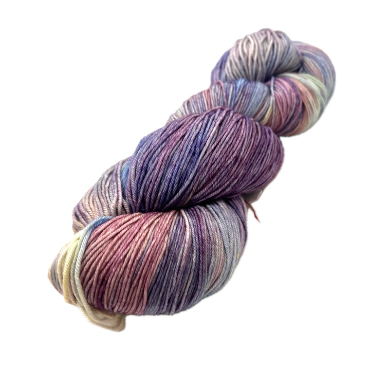 Variegated skein of yarn in pastel yellow, purples, and salmon pink, with a little blue green. 