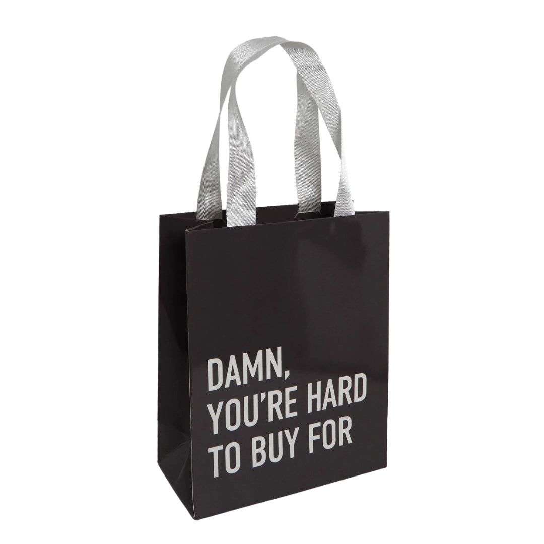 Dark gray gift bag with white handles that reads, "DAMN, YOU'RE HARD TO BUY FOR."