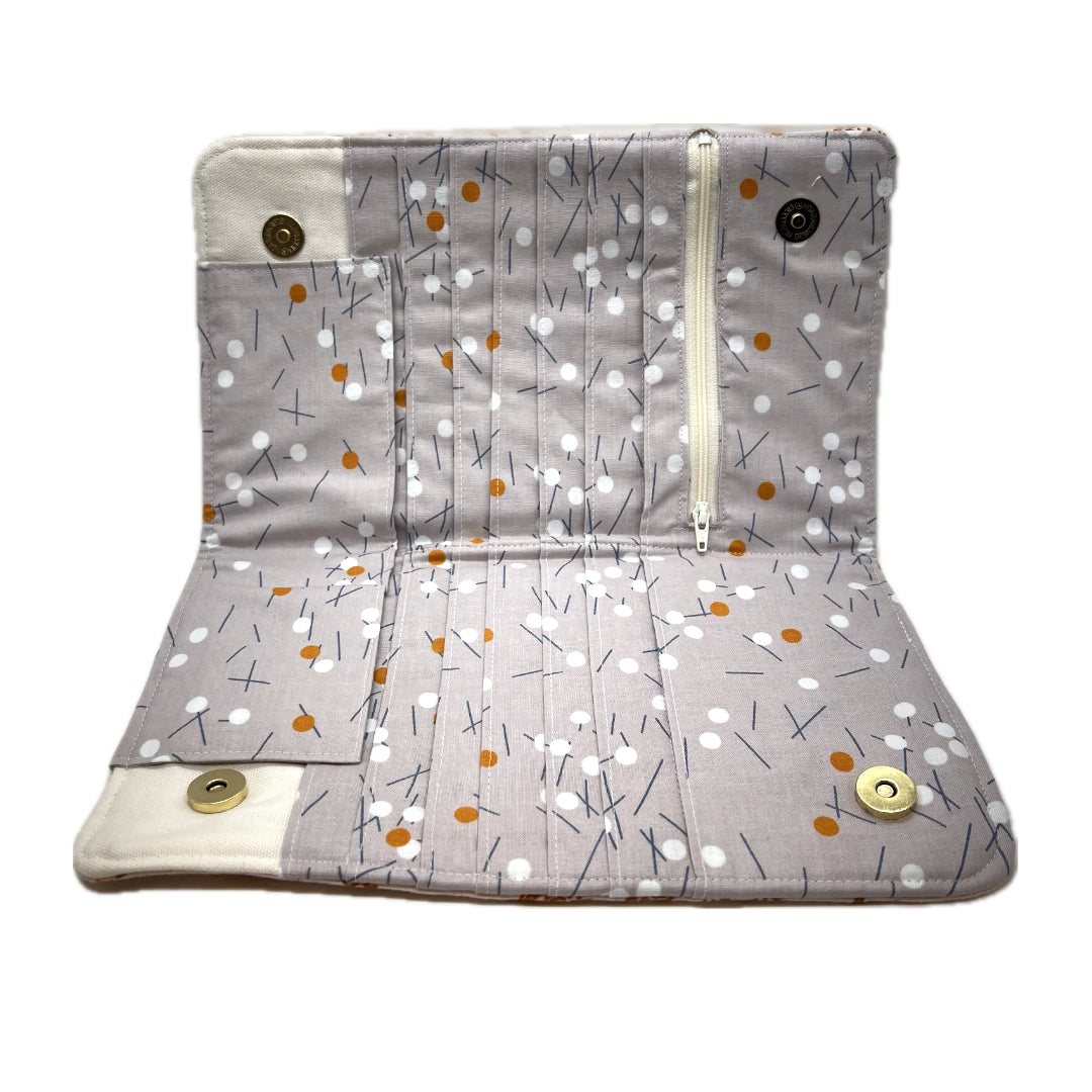 Inside of the needle organizer in  a light gray background, decorated with a pattern of small white dots, orange accents, and thin dark lines.