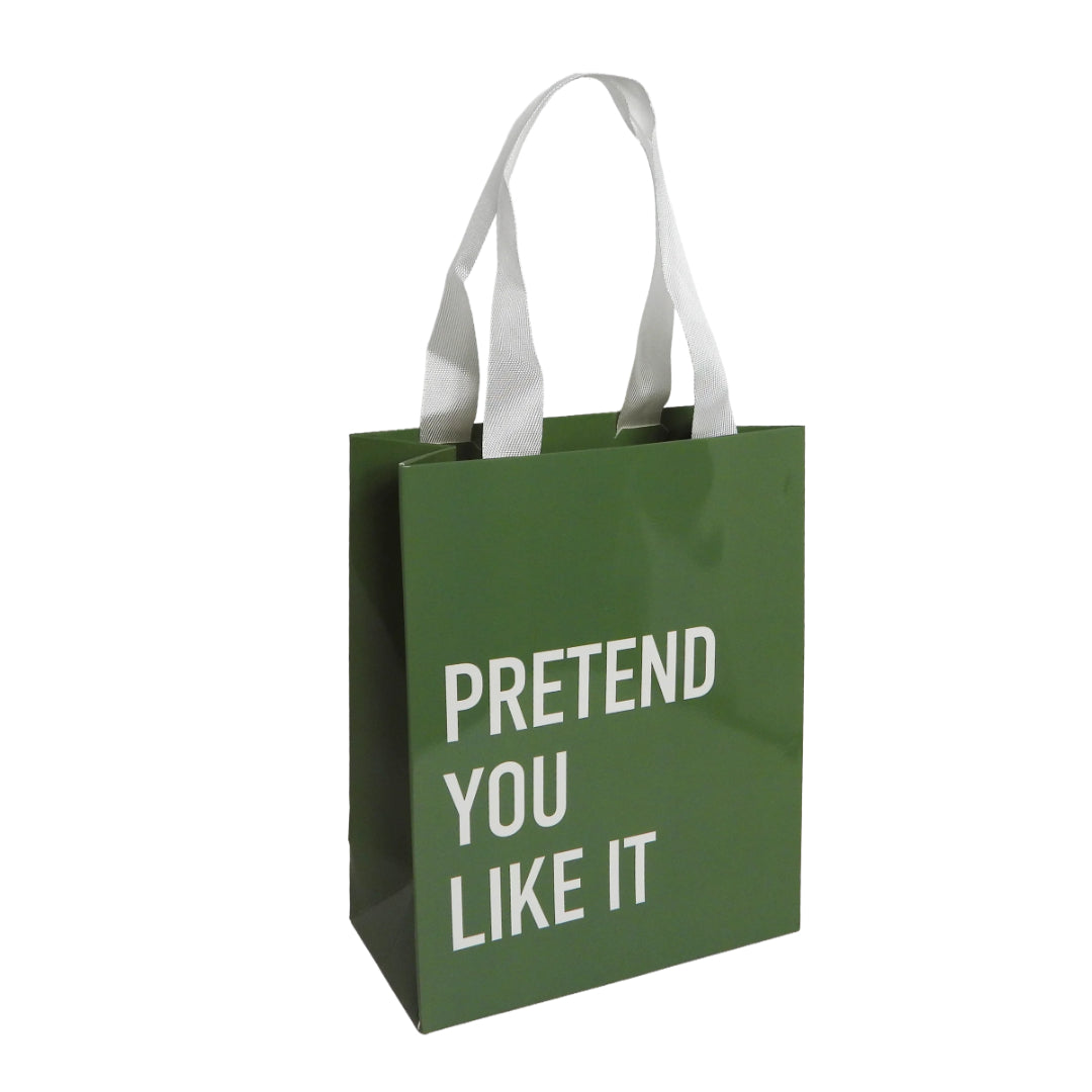 Green gift bag with a white handle which reads: PRETEND YOU LIKE IT.