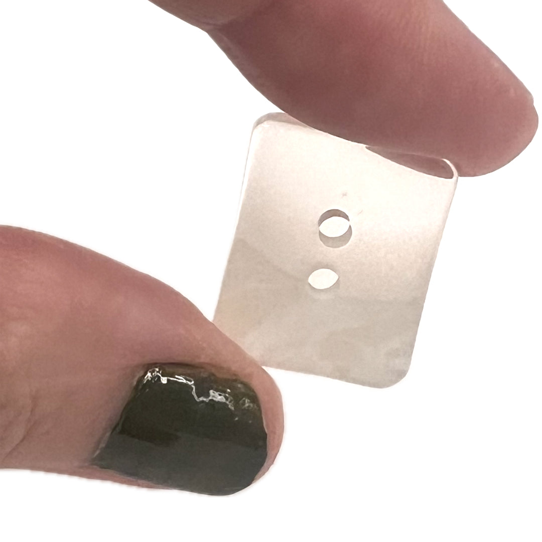 thumb and finger holding a rectangle button with 2 holes.
