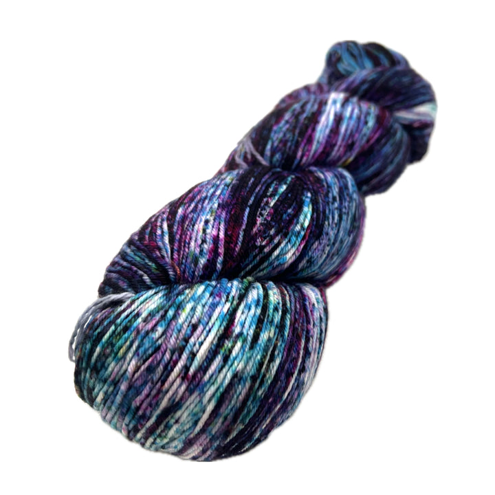 variegated skein of yarn in purples, teals, and white, speckled with blue.