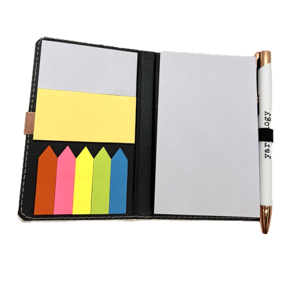 The inside of notebook with blank paper on the right and sticky notes on the left cover. The white pen attached has the Yarnology logo on it printed in black. 